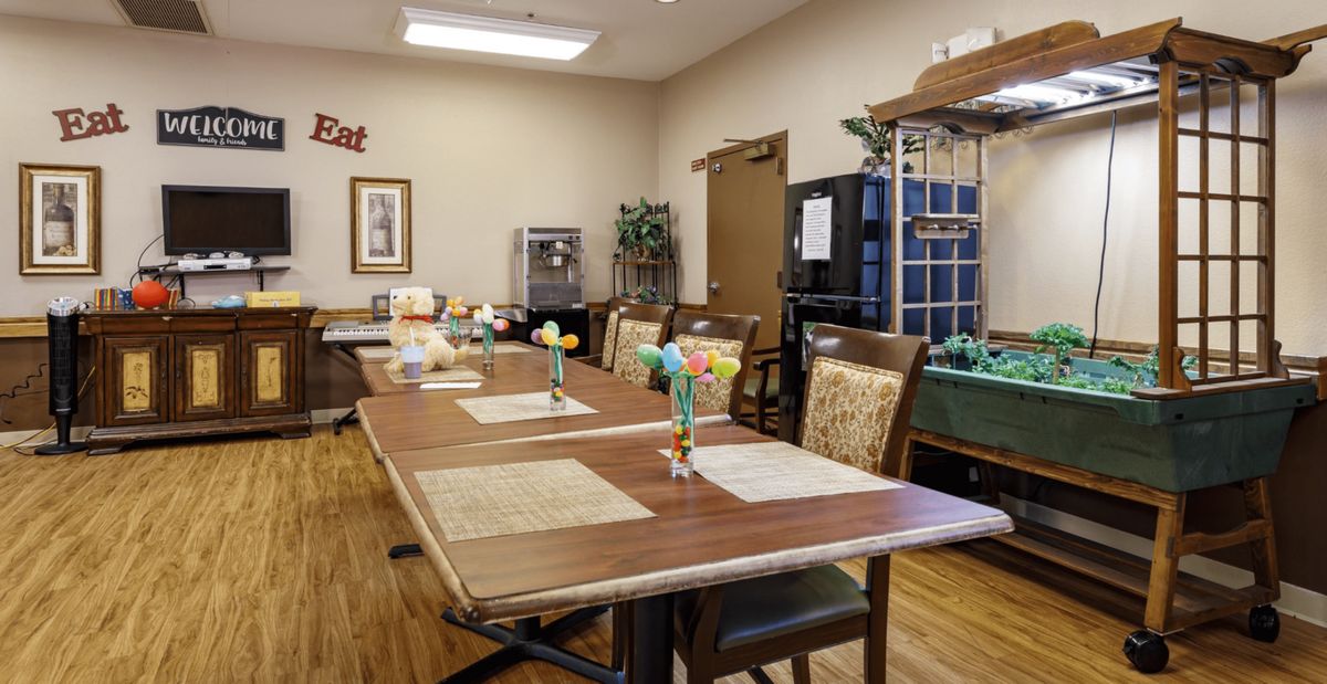 A cozy dining room with a long table set with placemats and chairs around it.