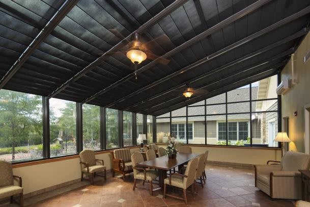 A cozy sunroom featuring a dining table, chairs, and large windows allowing natural light to fill the space.