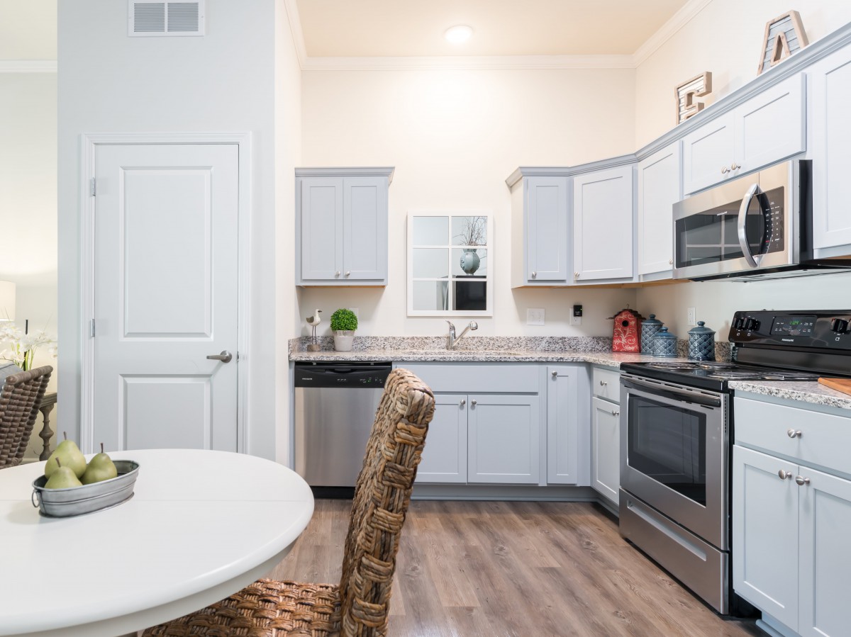 A modern kitchen with white cabinets, stainless steel appliances, and a small dining area.