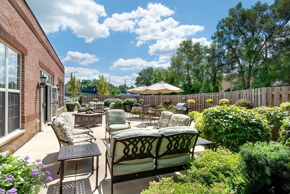 A sunny outdoor patio with comfortable seating and lush greenery.