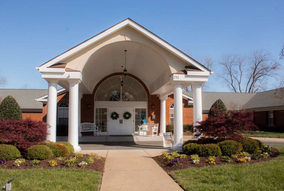 A building entrance featuring columns and well-maintained landscaping.