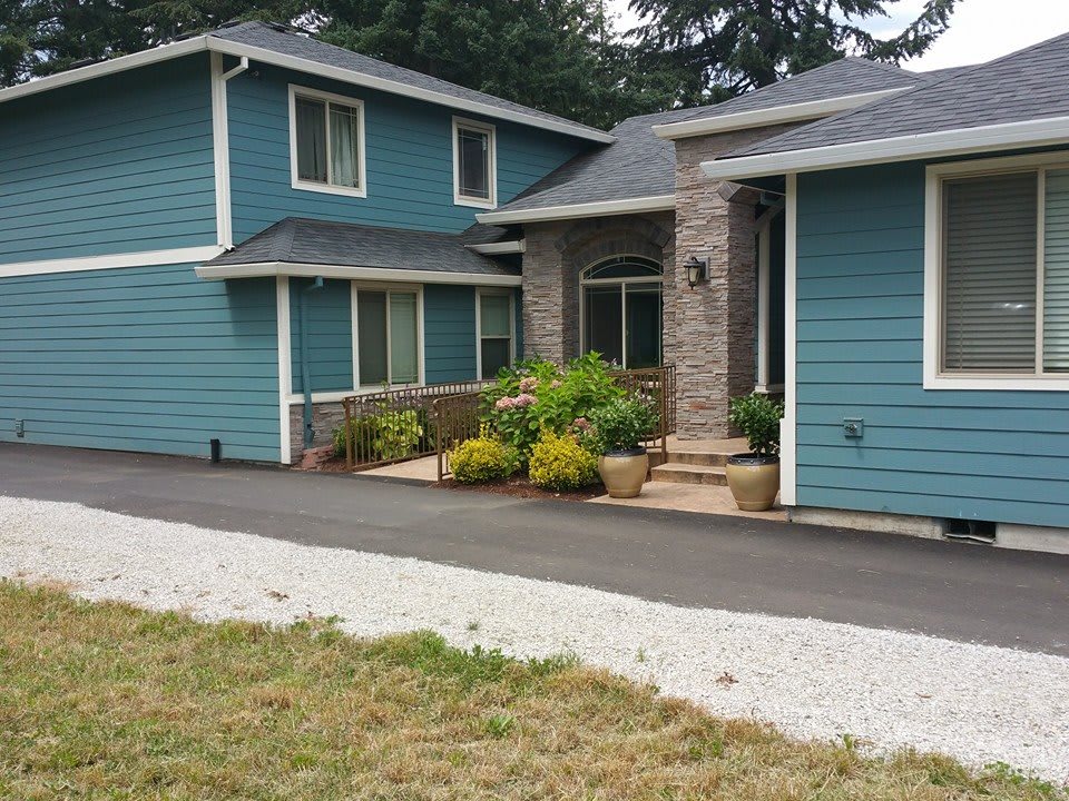A two-story residential house with blue siding and a landscaped front yard.
