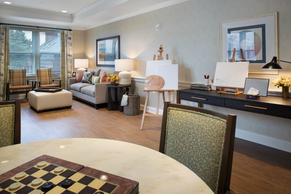 A modern living room featuring cozy seating, stylish art pieces, and a chessboard for leisure.