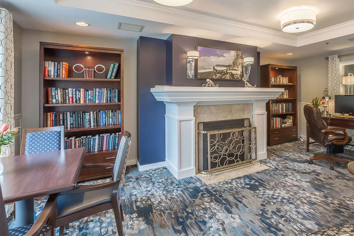 A cozy library room with a fireplace and bookshelves.