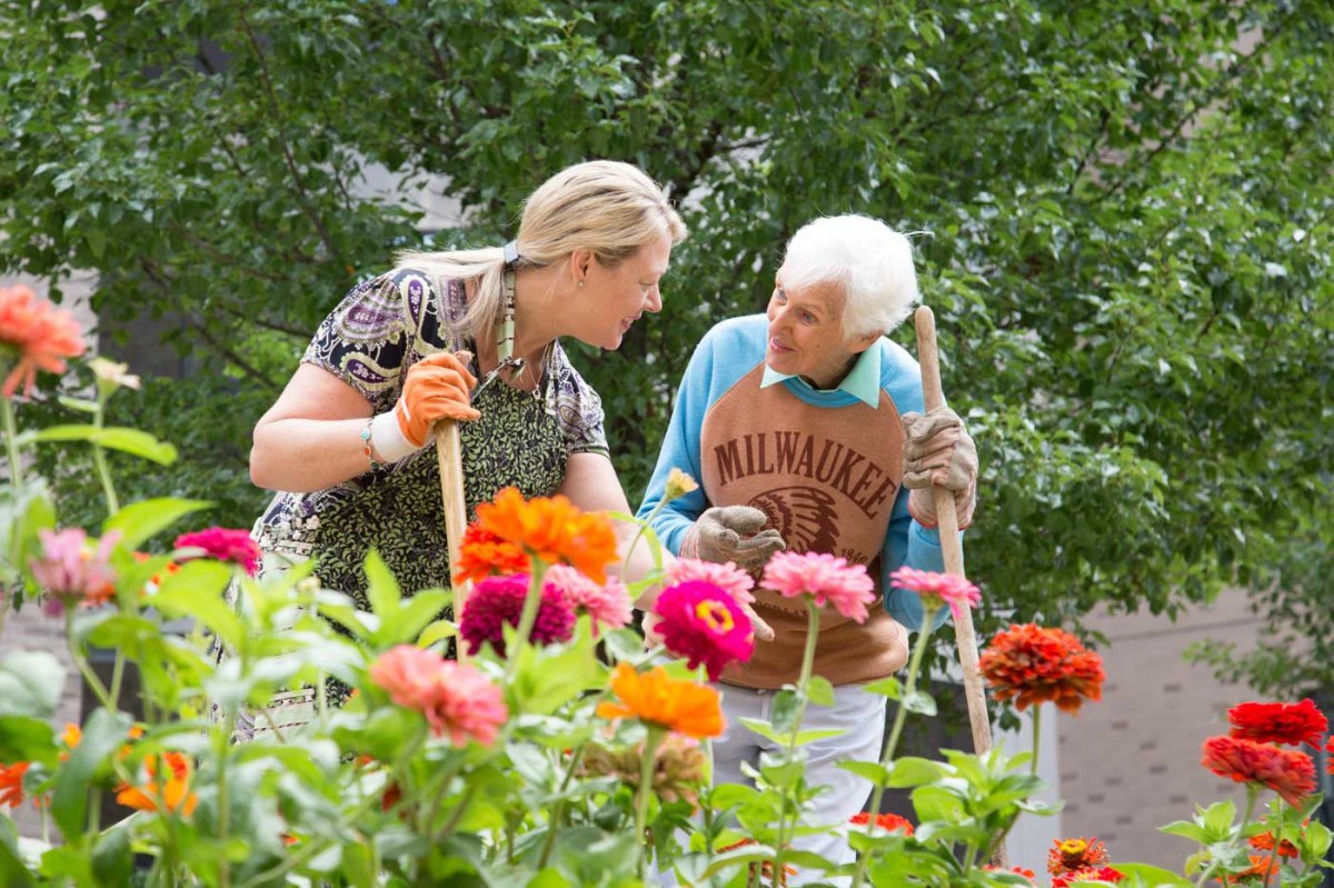 Two people enjoying gardening together surrounded by colorful flowers.