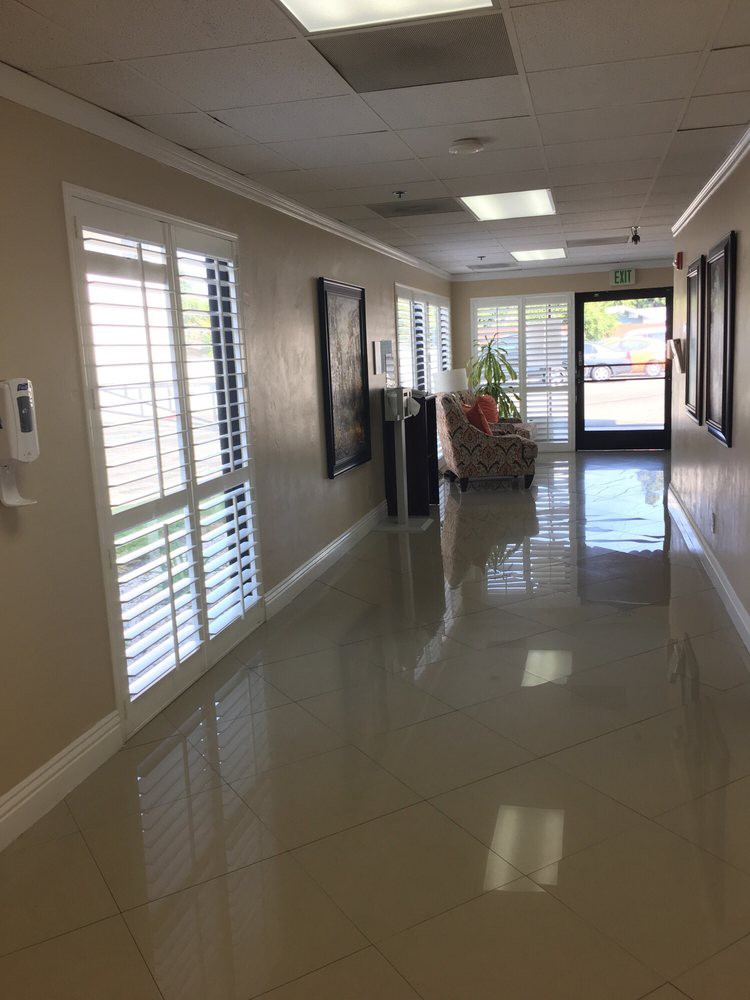 A clean, well-lit hallway with shiny floors and large windows.