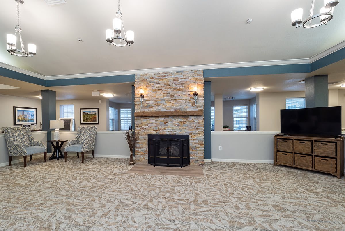 A spacious living room with a stone fireplace, carpeted floor, and cozy furniture.