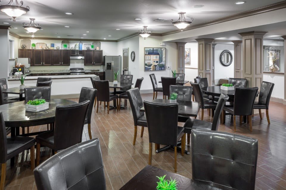 A modern dining area with neatly arranged tables and chairs, featuring wood flooring and contemporary decor.