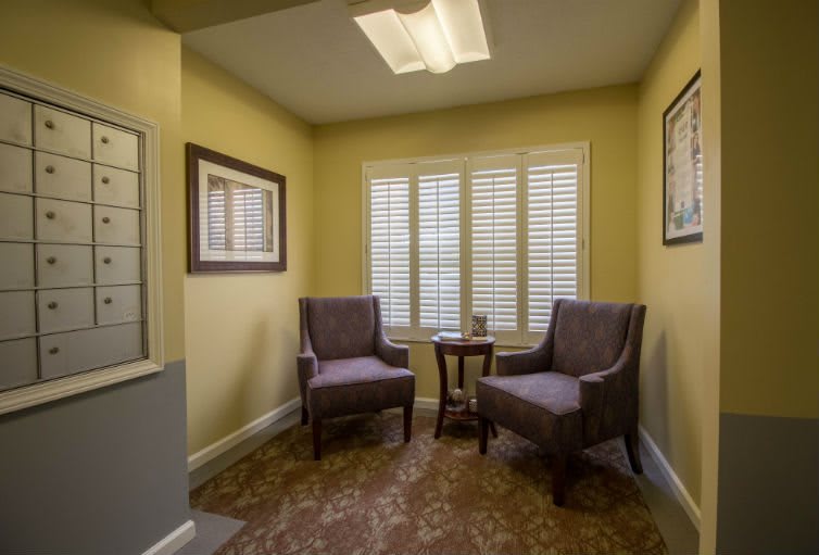 A cozy waiting room with two chairs, a small table, and wall art.