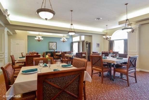 An empty restaurant interior with neatly set tables and elegant chandeliers.