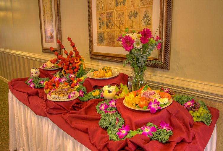 A beautifully arranged buffet table with colorful floral decorations and a variety of dishes.