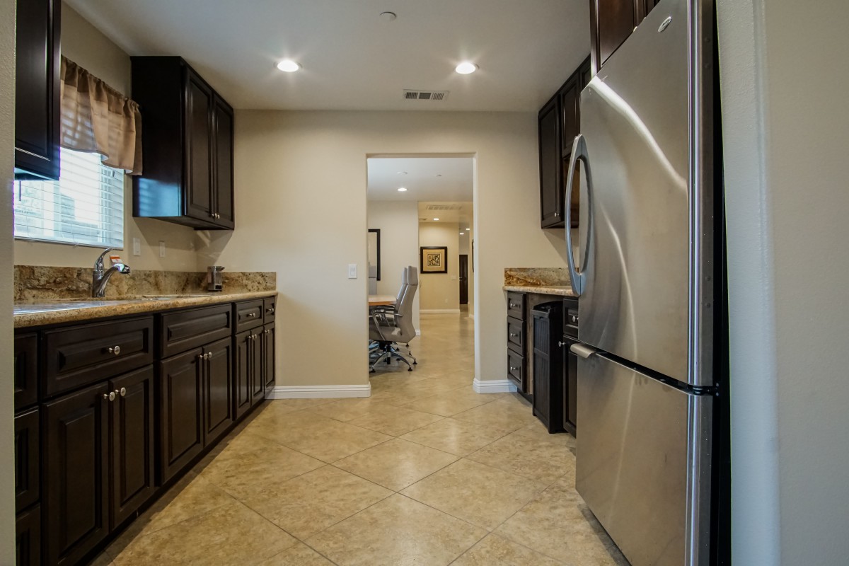 A modern kitchen with dark cabinets and stainless steel appliances.