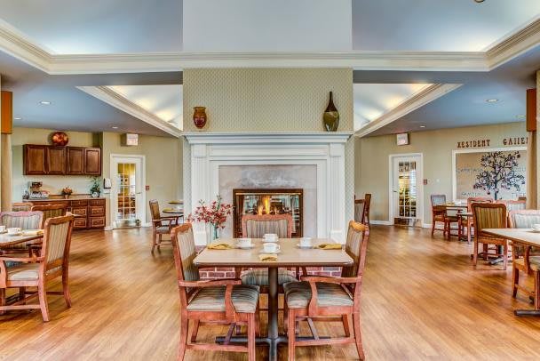 A cozy dining area featuring a central fireplace, wooden tables and chairs, and a modern interior design.