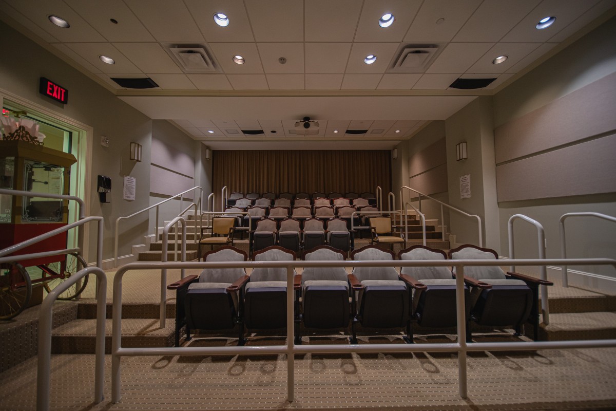 An empty auditorium with rows of seats and a small stage at the front.