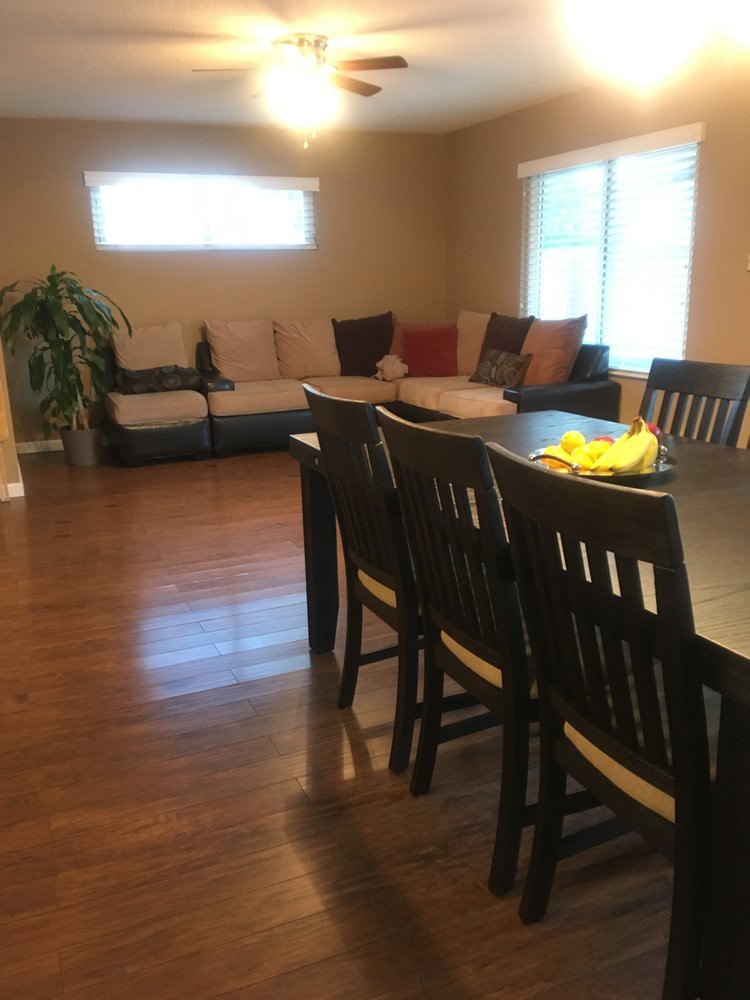 A modern living room with a dining table, chairs, and a cozy sofa on a wooden floor.