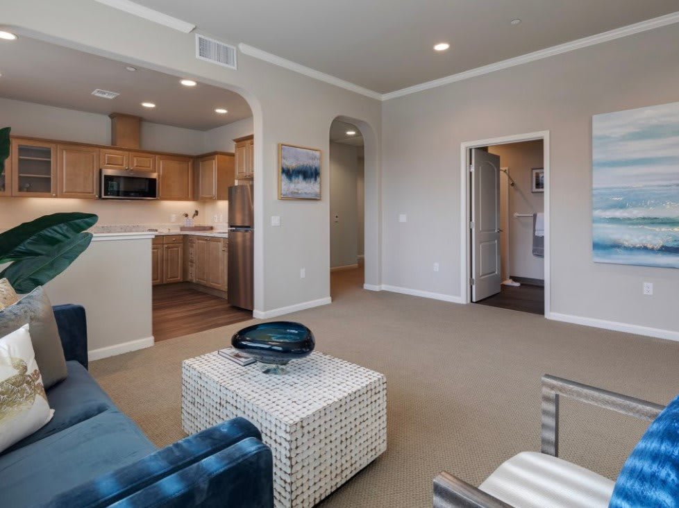 A modern living space featuring an open floor plan with a view of the kitchen.