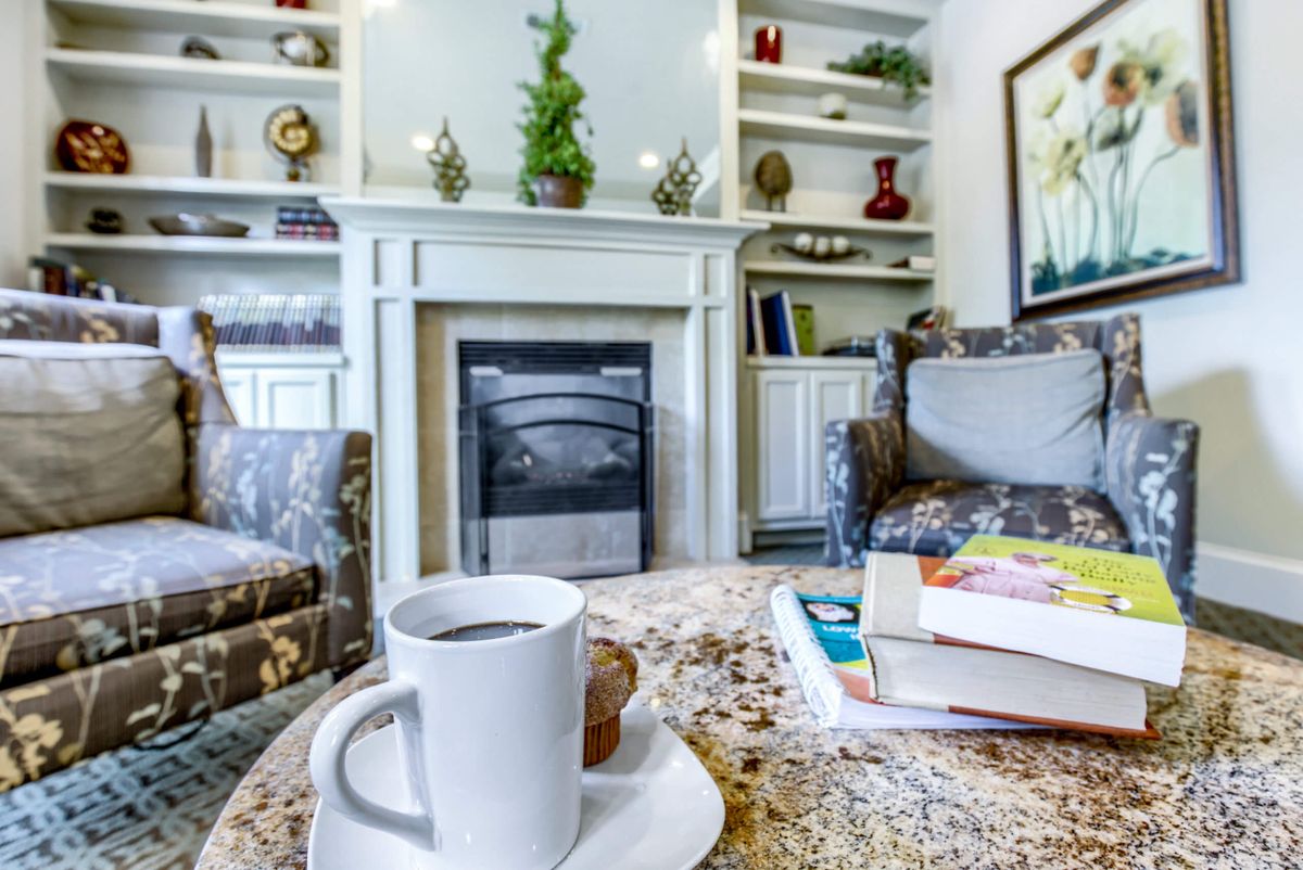 A cozy living room with a cup of coffee and books on the table in front of a fireplace.