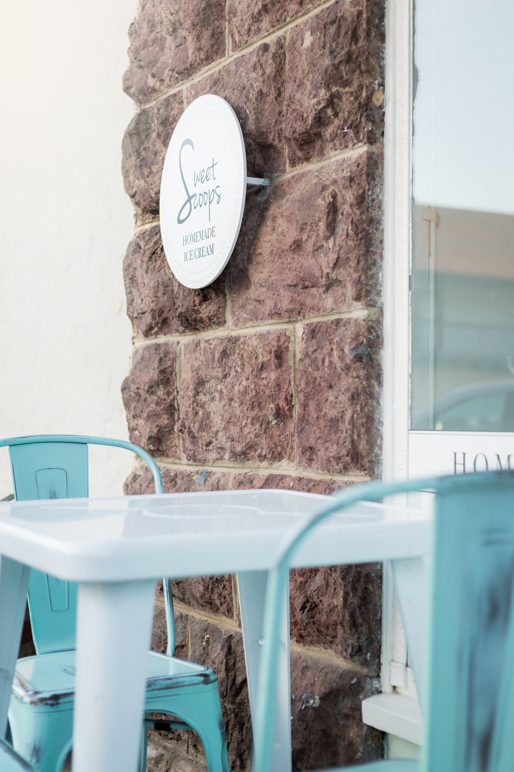 A quaint cafe with pastel colored chairs and a rustic brick wall.