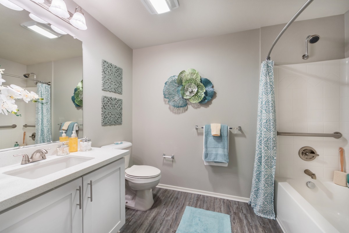 A modern bathroom with stylish decor, featuring a shower curtain, wall art, and neatly arranged towels.