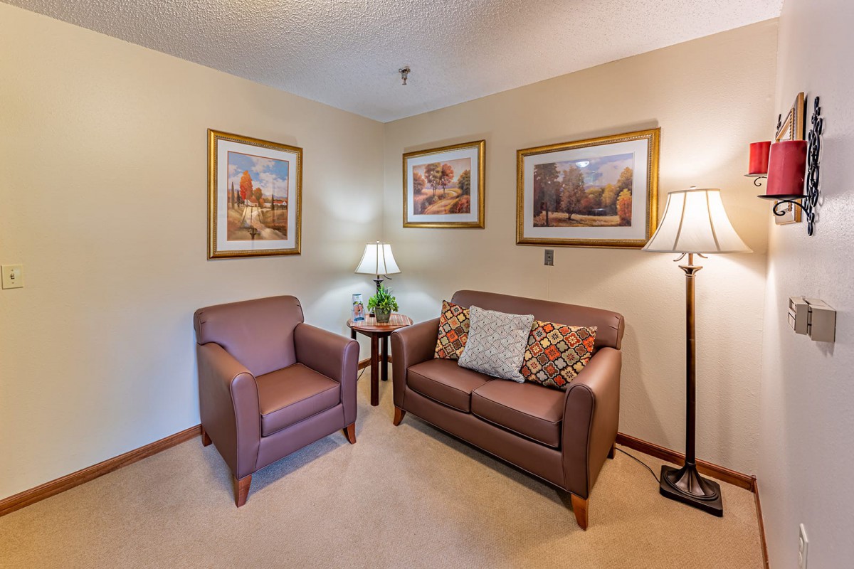 A cozy living room corner with a couch, armchair, and decorative lamps.
