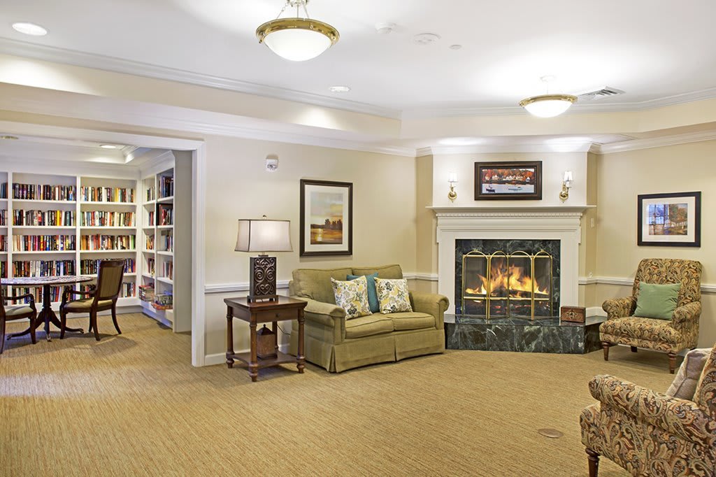A cozy living room featuring a fireplace, sofa, and bookshelf.