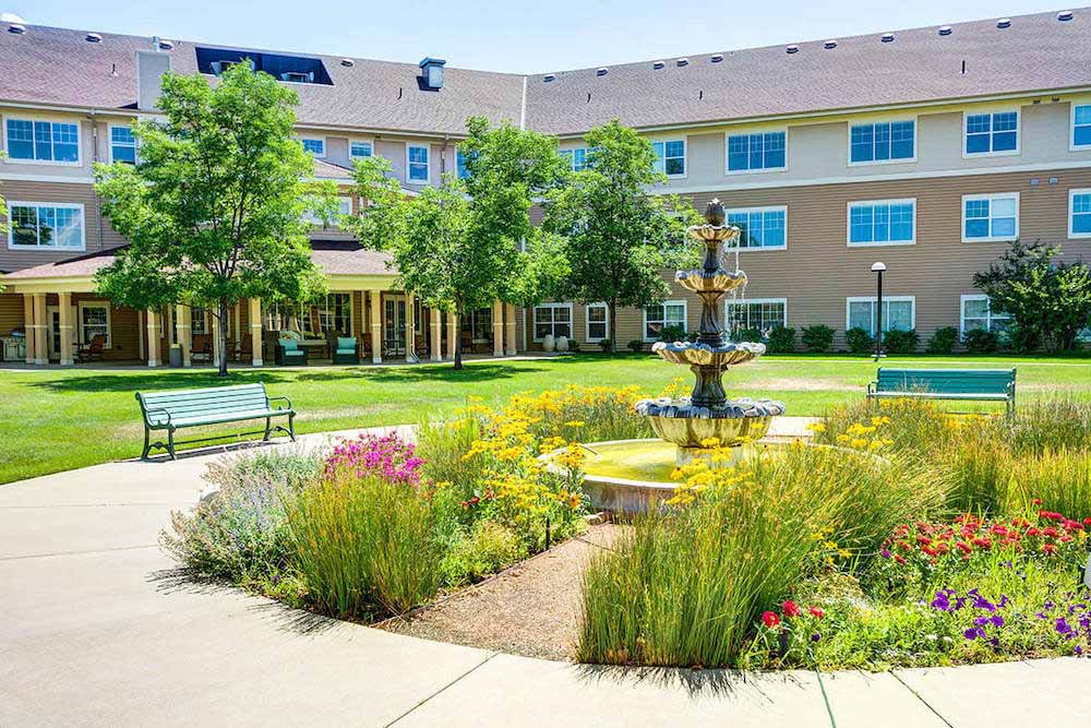 A well-maintained courtyard featuring a central fountain, surrounded by lush gardens and seating areas.