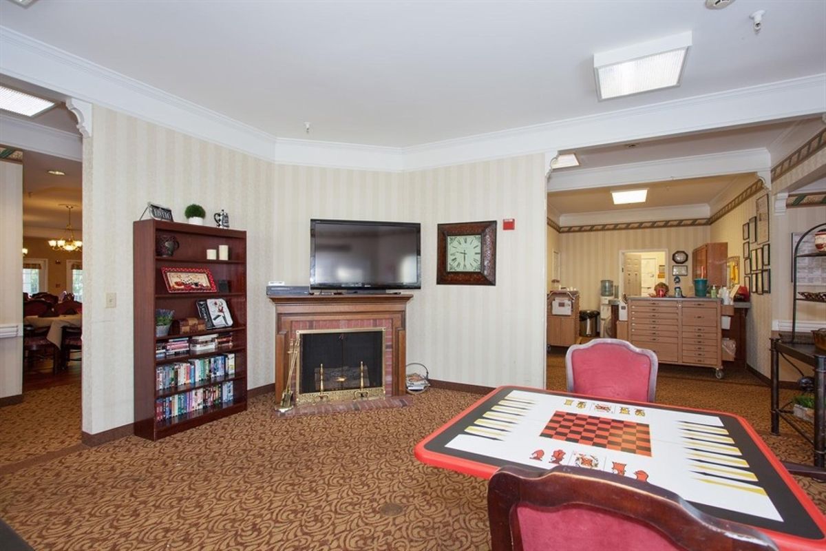 A cozy living room with a fireplace, TV, bookshelf, and a game table.