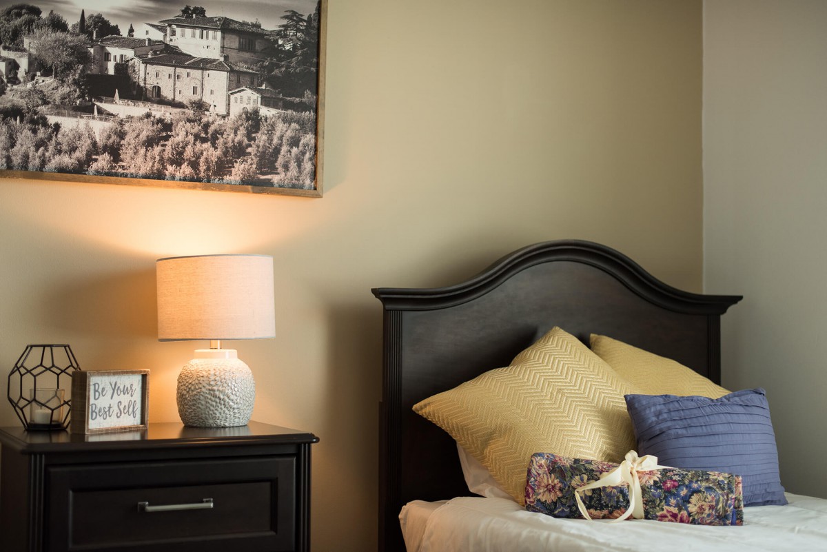 A cozy bedroom with a neatly arranged bed, nightstand, and lamp.