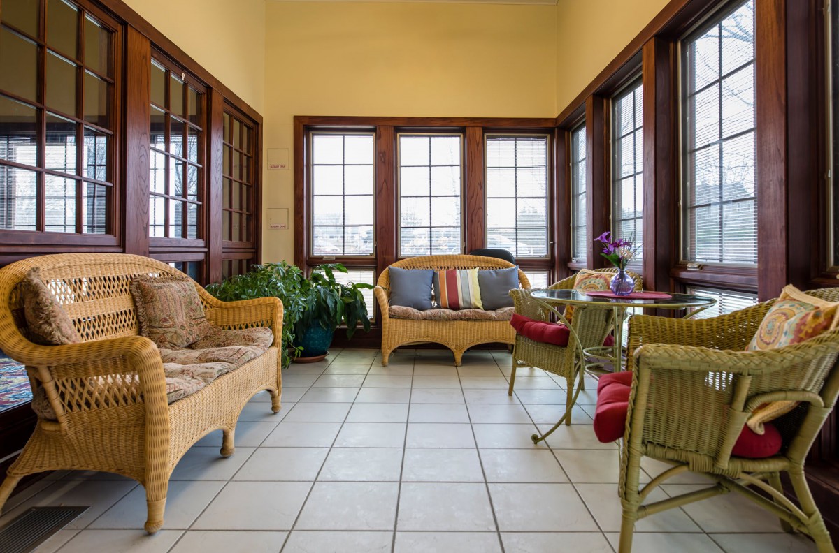 A cozy sunroom with wicker furniture, featuring comfortable seating and large windows allowing natural light to pour in.