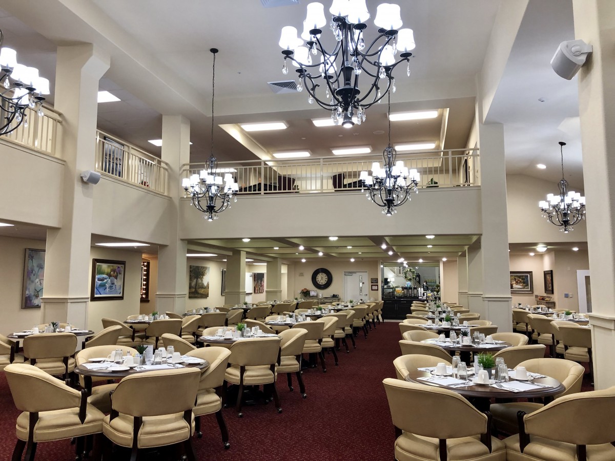 An elegant restaurant dining area with chandeliers, neatly set tables, and a warm ambiance.
