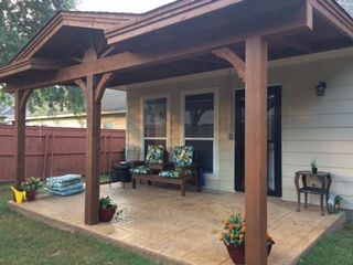 A cozy patio with wooden posts, outdoor seating, and potted plants.