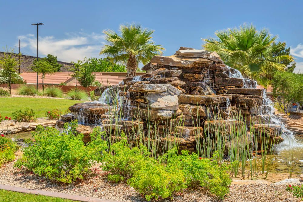 A landscaped garden featuring a cascading rock waterfall surrounded by lush greenery.