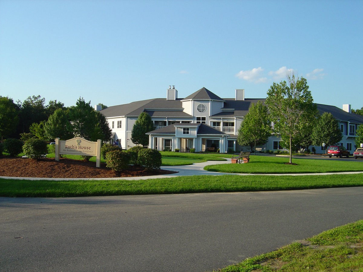 A large suburban house with a well-maintained lawn and surrounding trees.