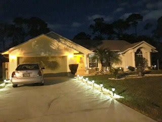 A suburban house illuminated at night with pathway lights leading up to the entrance.
