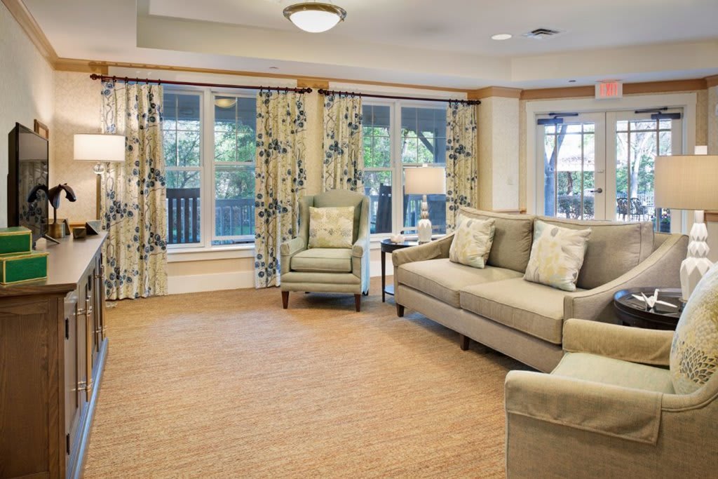 A cozy living room with a sofa, armchair, and patterned curtains creating a warm and inviting atmosphere.
