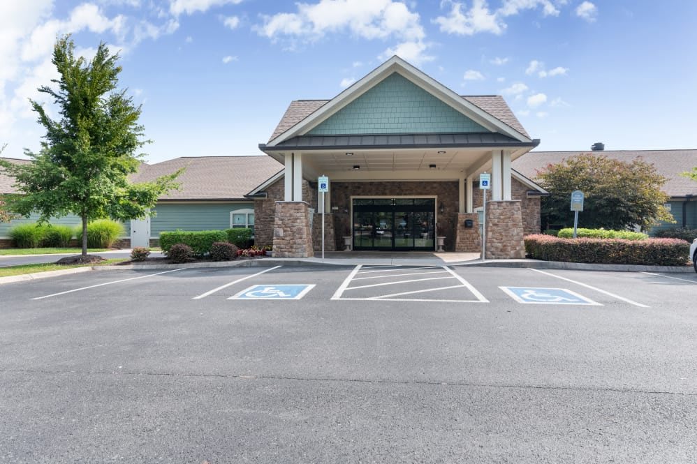 The image depicts the entrance of a commercial building with a parking lot and handicap-accessible parking spaces.