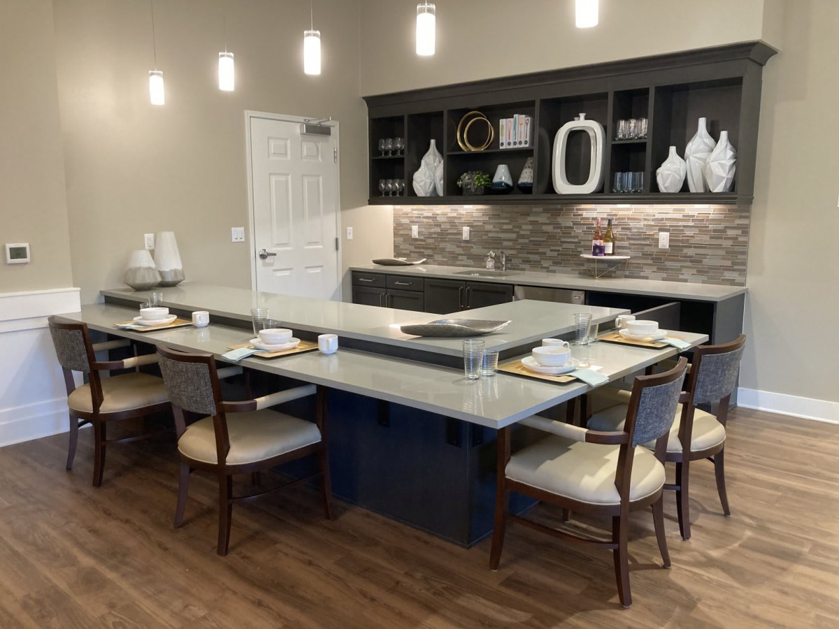 A modern kitchen with a large island and dining area, featuring elegant table settings and contemporary decor.