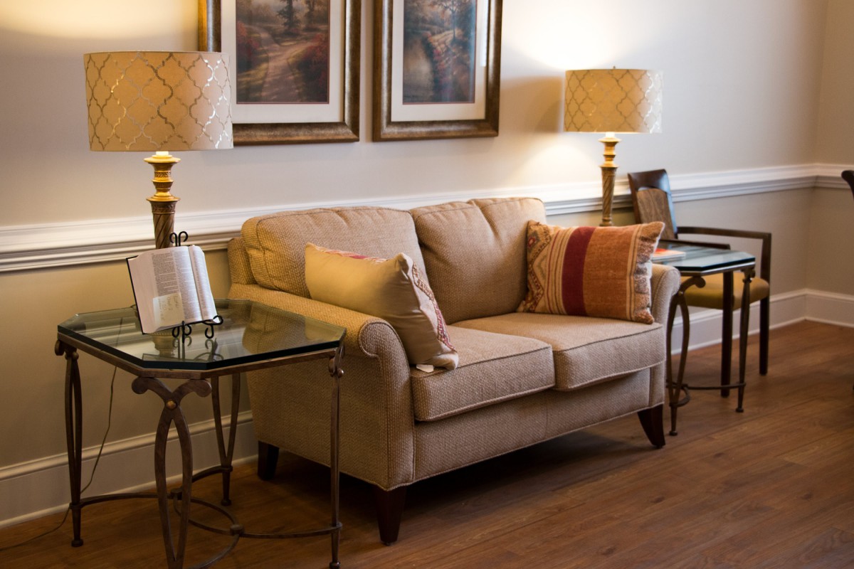 A cozy living room with a comfortable beige sofa, decorative cushions, and warm lighting from table lamps.