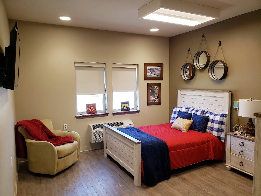 A modern bedroom with red and blue bedding, featuring cozy decor and a comfortable chair.
