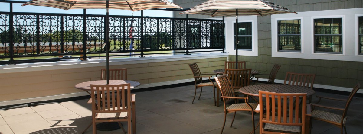 An outdoor patio area with tables, chairs, and umbrellas surrounded by a decorative privacy screen.
