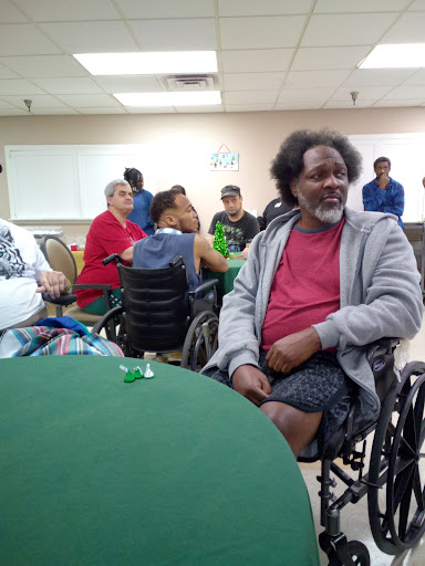A community gathering featuring individuals in wheelchairs, engaging with one another in a warm and friendly indoor environment.