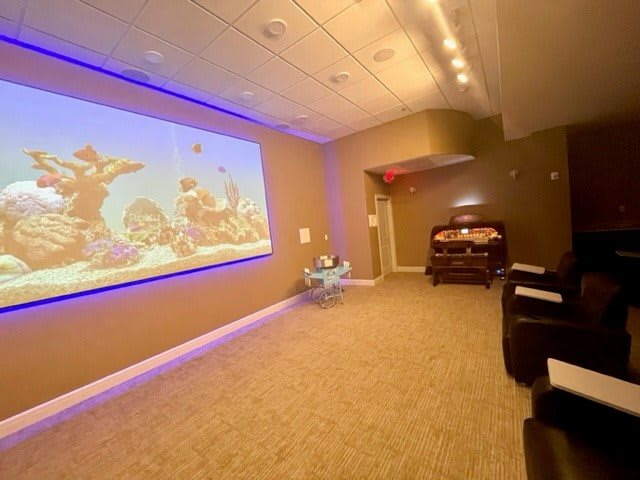 A cozy home theater setup featuring a large projector screen, comfortable recliner chairs, and ambient lighting.