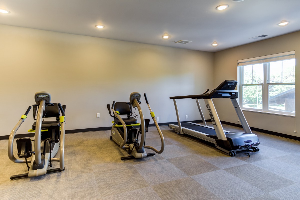 A small gym with exercise equipment including a treadmill and an elliptical machine.