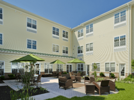 A view of a building with a courtyard featuring outdoor seating and umbrellas.