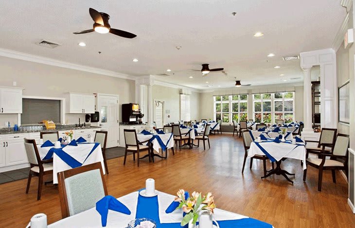A well-lit dining room with neatly arranged tables and blue napkins.