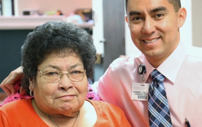 A smiling professional poses with an elderly woman.