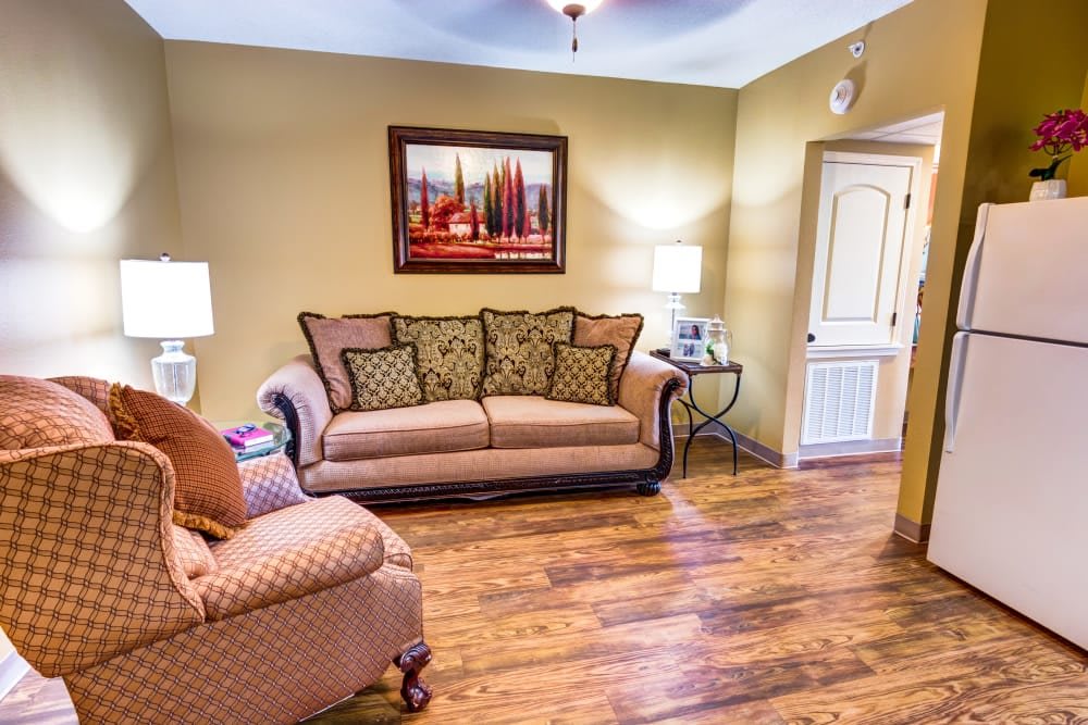 Cozy living room with a patterned sofa and armchair, wooden floors, and warm lighting.