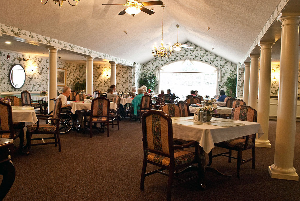 A cozy restaurant interior with tables set for dining, featuring elegant chandeliers and a relaxed atmosphere.