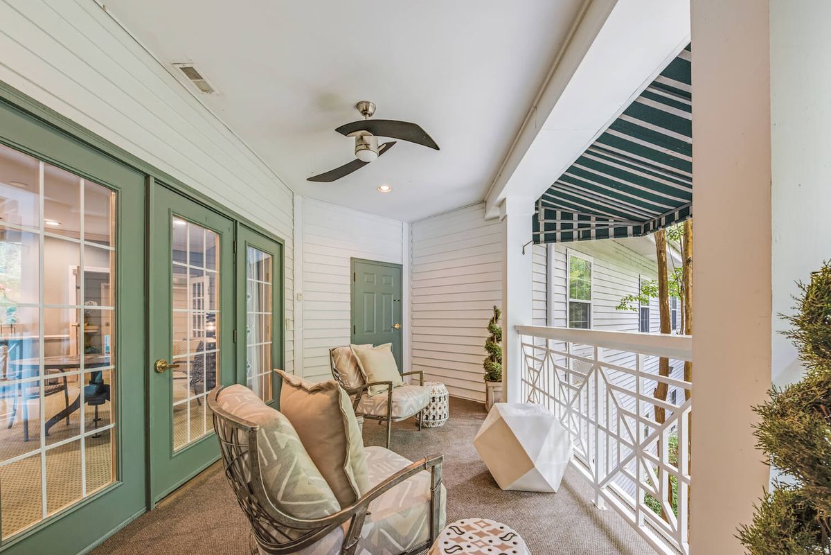 A cozy porch with comfortable seating and overhead ceiling fans, perfect for relaxing under the striped awning.