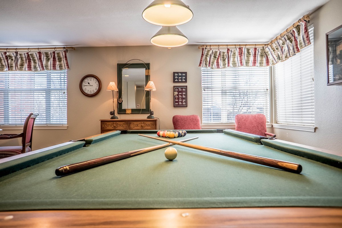 A cozy billiard room with a well-kept pool table and comfortable seating.